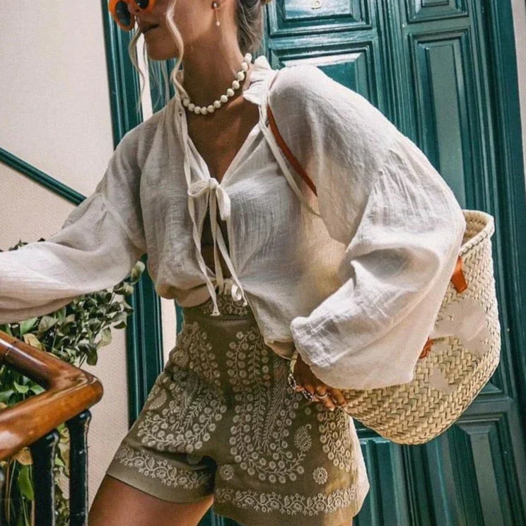 Detailopname van het delicate bloemenborduursel op beige dames shorts met hoge taille.