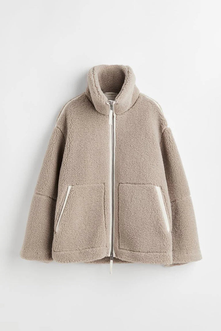 Modieuze beige teddy tussenjas voor dames, ruimvallend design met opstaande kraag, geschikt voor herfst en milde winter.
