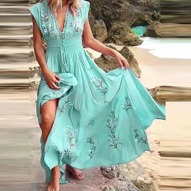 Blauwe dames zomerjurk, maxi lengte, met sierlijke borduursels en diepe V-hals. Ideaal als strandjurk.
