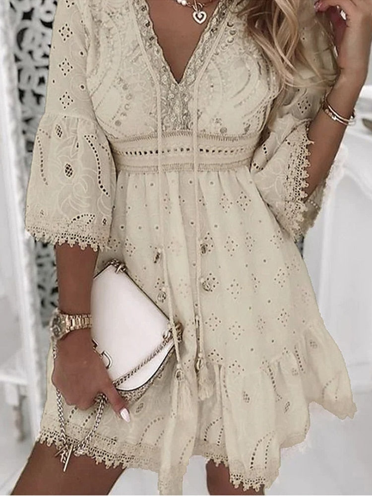 Vrouwelijke beige/witte bohemian zomerjurk met diepe v-hals. Luchtige stof, ideaal voor warme dagen en als elegante strandjurk.