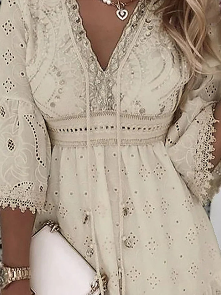 Comfortabele beige/witte zomerjurk met bohemian flair. Luchtige pasvorm en v-hals voor een vrouwelijke, zomerse look.