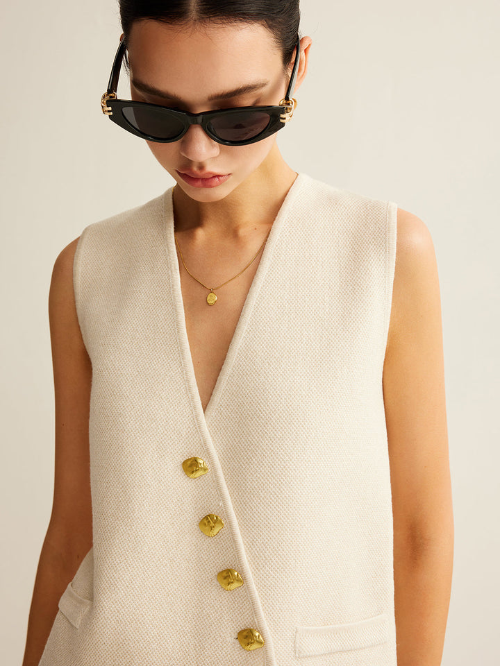 Damesvest met unieke knoopsluiting, gebreid en asymmetrisch, voor een moderne en elegante uitstraling.