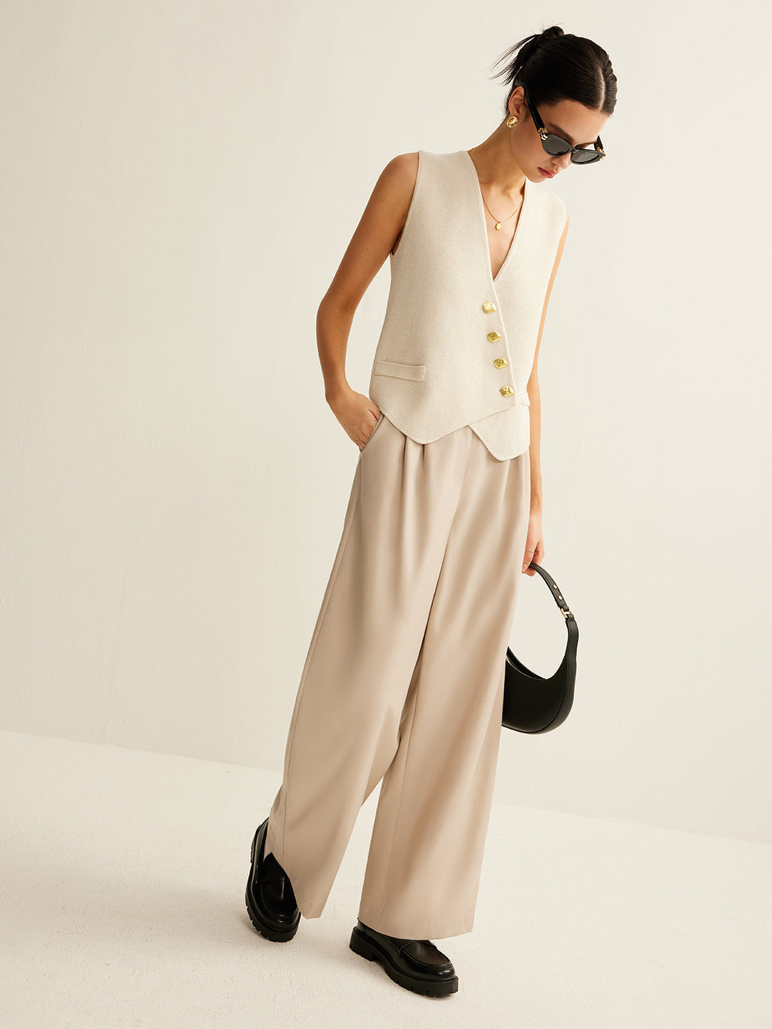Vrouw draagt stijlvol asymmetrisch gebreid damesvest met knoopsluiting, comfortabel en modieus.