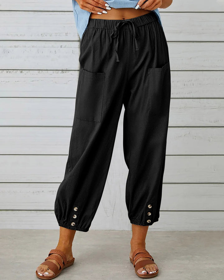 Volledige foto van een vrouwelijke broek met hoge taille, rechte pijpen en opvallende knoopdetails.