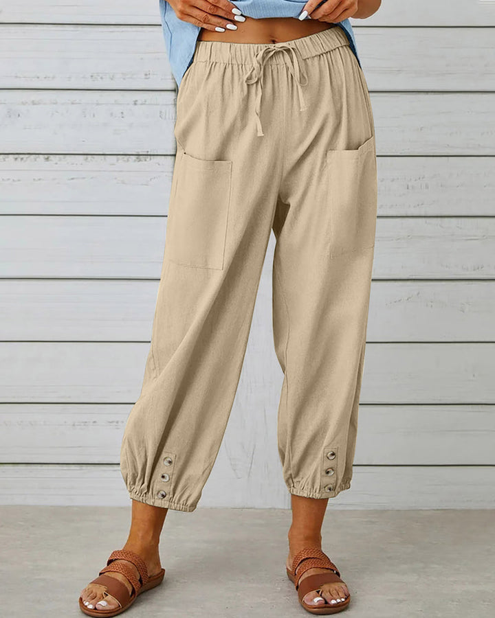 Close-up van de hoge taille en decoratieve knoopdetails op deze stijlvolle dames broek.