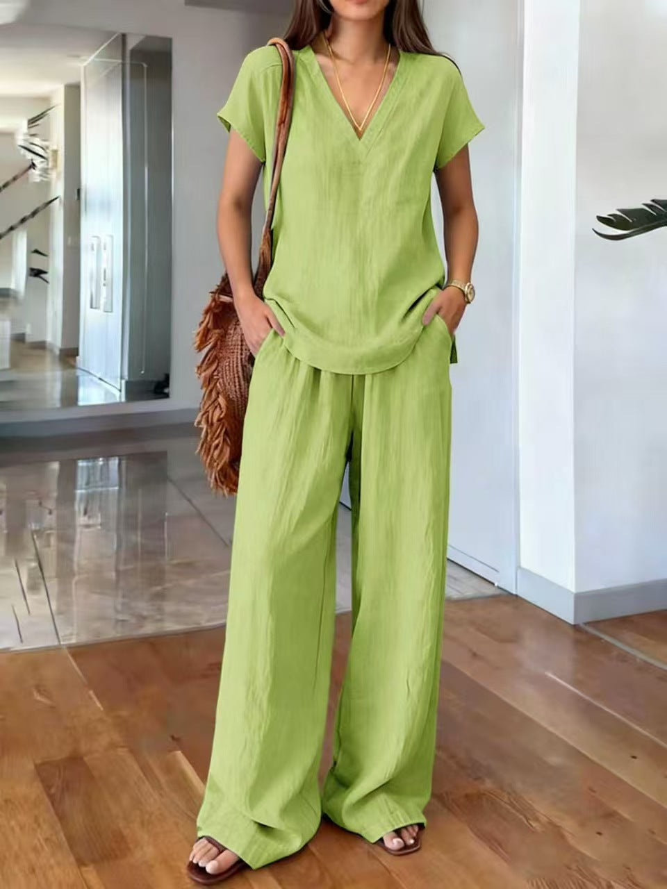 Volledig zicht op een model dat de casual linnen tweedelige set draagt met V-hals blouse en broek.