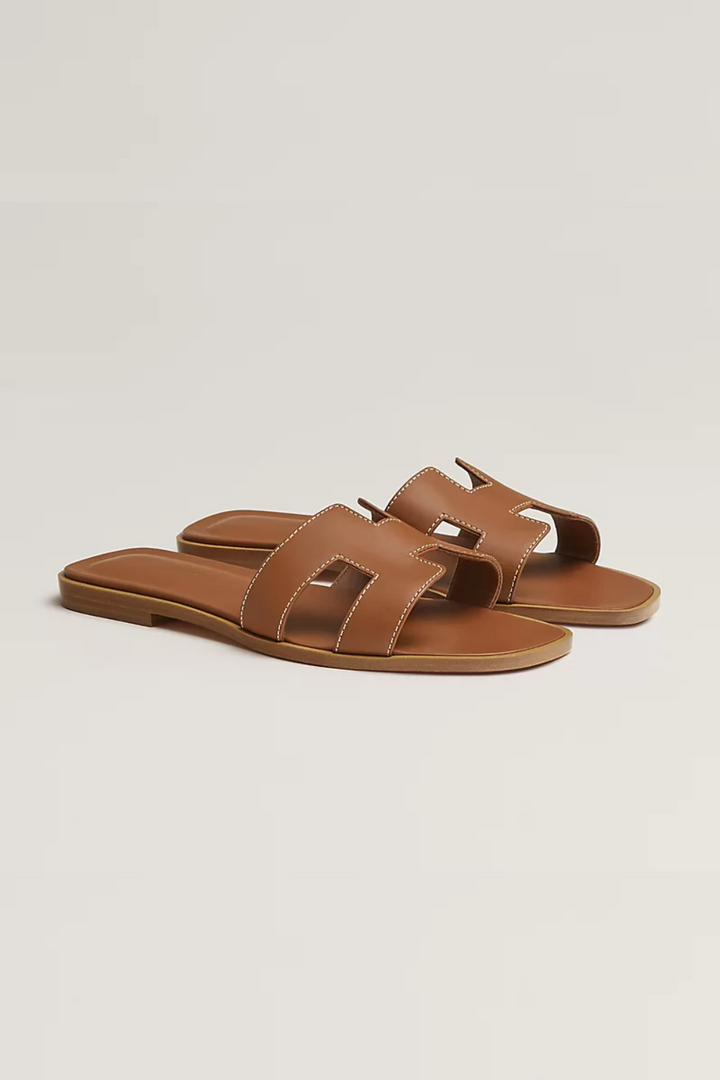 Vrouw draagt comfortabele dames teenslippers. Perfecte platte sandalen voor een zomerse dag aan het strand of casual mode.