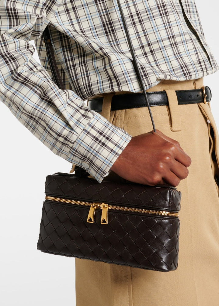 Elegante gevlochten schoudertas in detail, toont luxe gouden gespen en stevige constructie.