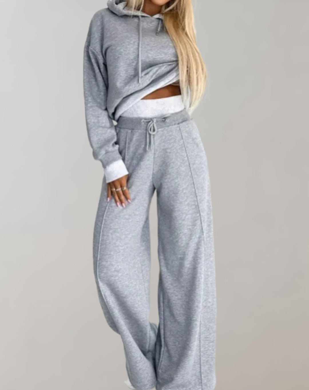 Damesmodel draagt dit trendy joggingpak met crop hoodie en wide-leg broek. Perfecte pasvorm voor een sportieve casual look.