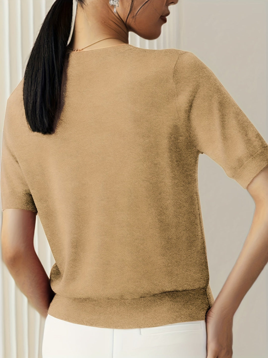 Model draagt comfortabele dames korte mouw trui, ronde hals, staand in lentezon.