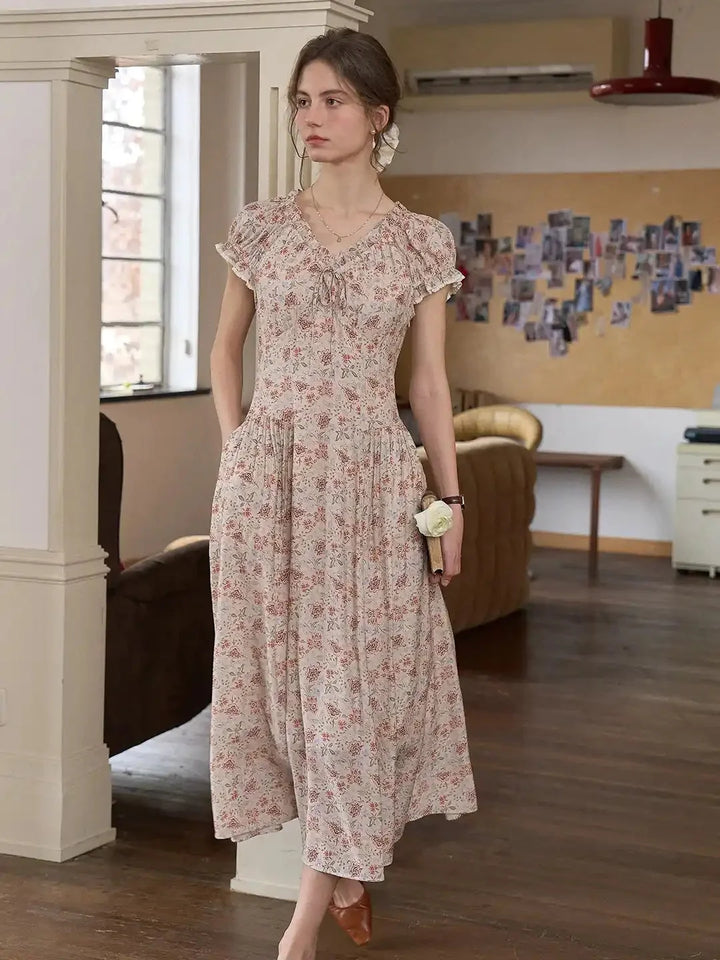 Model draagt een modieuze kaki midi jurk met bloemenprint, V-hals en korte mouwen.