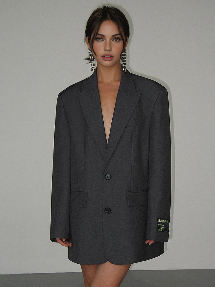 Grijze oversized dames blazer met open pasvorm, casual gedragen over jeans voor een modieuze look.
