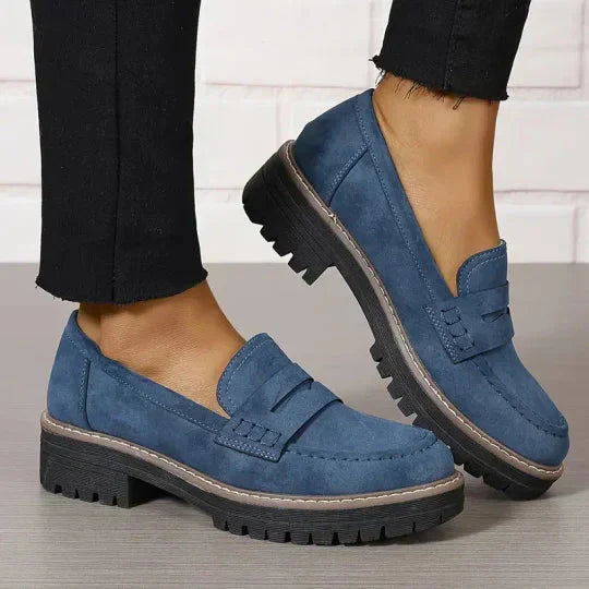 Zijzicht van zwarte dames penny loafers met dikke zool, benadrukt de robuuste en toch elegante constructie.