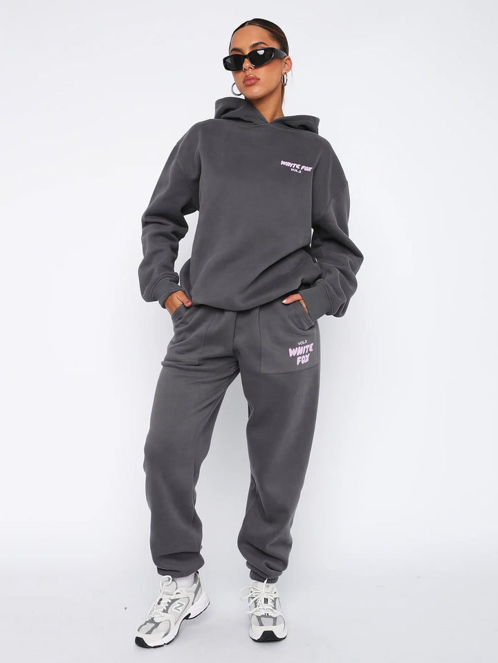 "Dames trainingspak met oversized pasvorm, wit, elastische ribboorden, trendy puffprint logo en fleecestof."