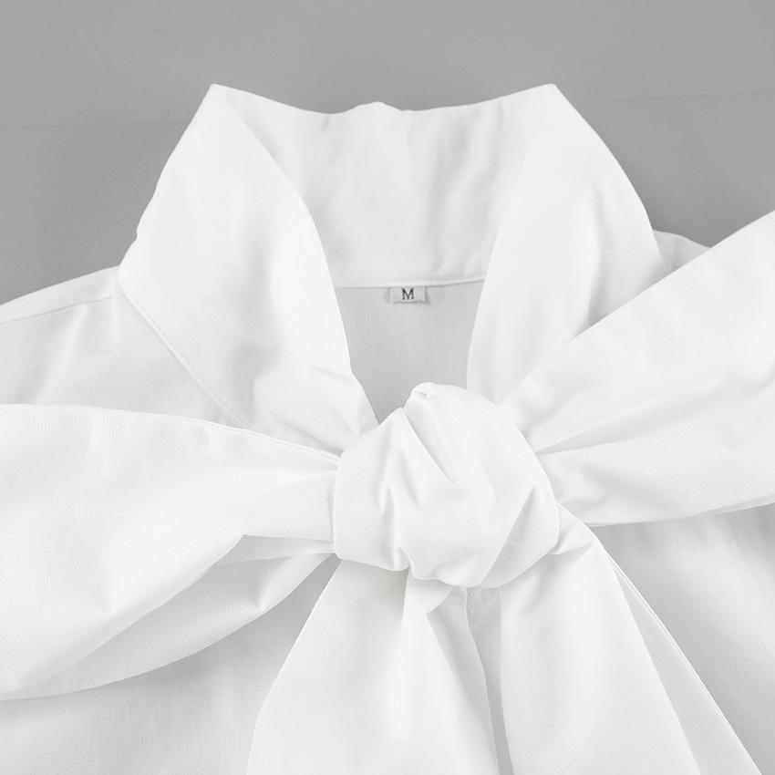 Detail van de elegante strik op het witte dames overhemd, voor een klassieke en verfijnde uitstraling.