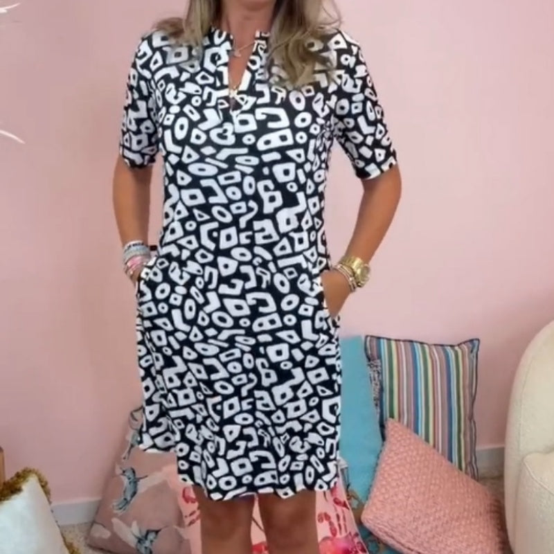 Dames v-hals minijurk, korte mouwen, met uniek geometrisch motief. Stijlvolle en luchtige zomerjurk.