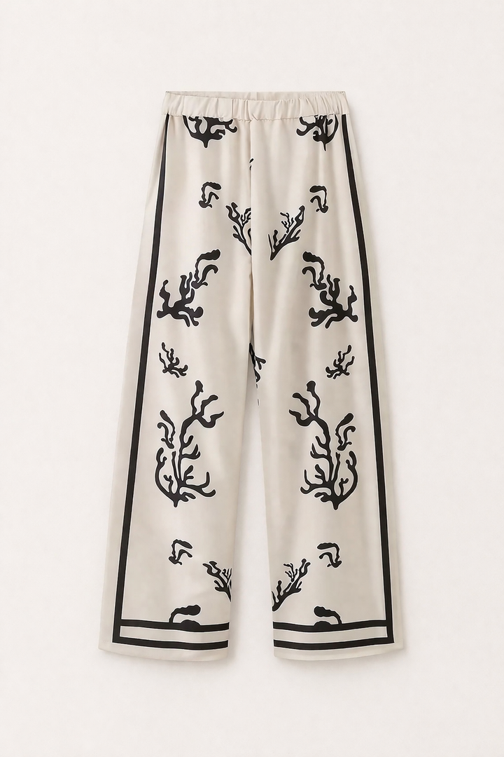 Model toont casual chic beige damesset met pioenroos print blouse en wijde broek voor een elegante zomerlook.