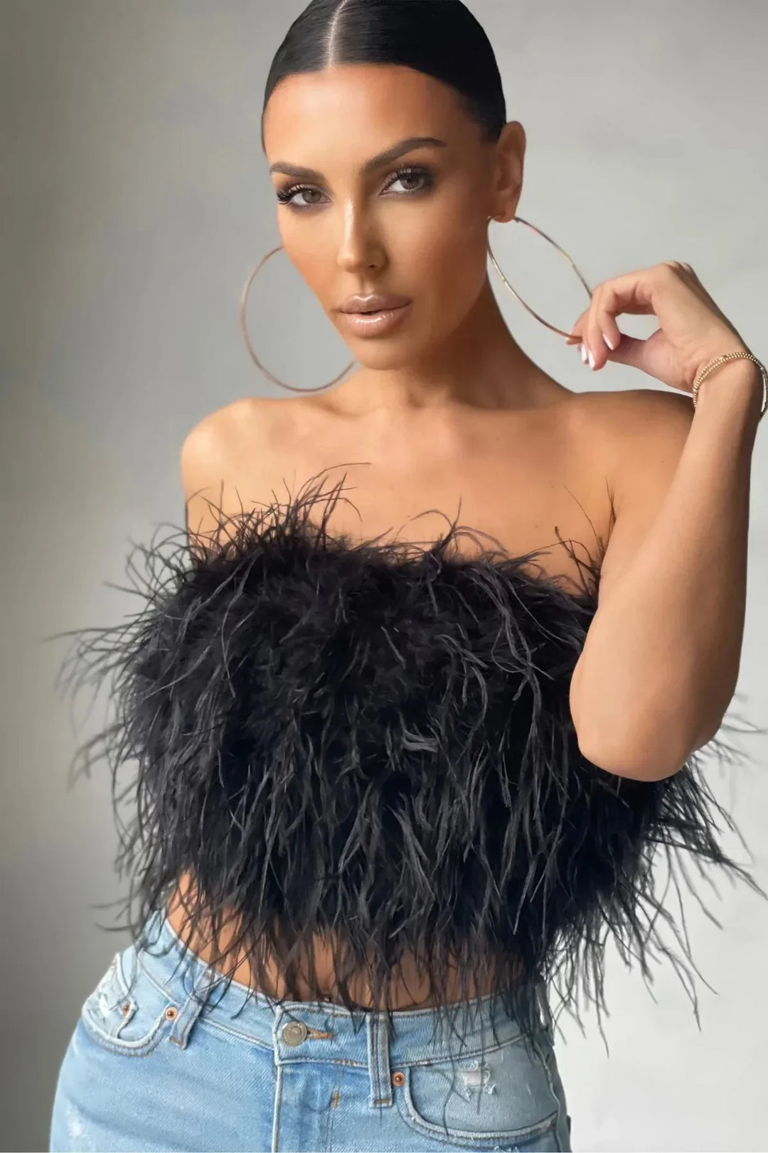 Modebewuste mouwloze crop top met elegant veren detail, ideaal als feesttop.