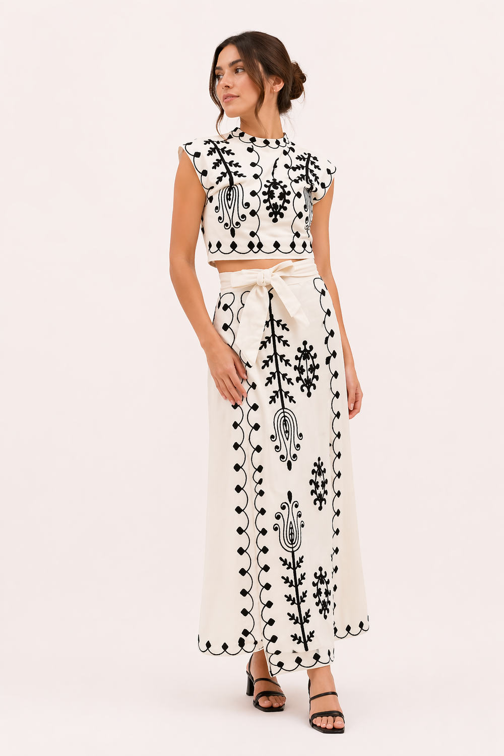 Close-up van geborduurde midirok en korte top set, straalt elegantie en zomerse vibe uit.