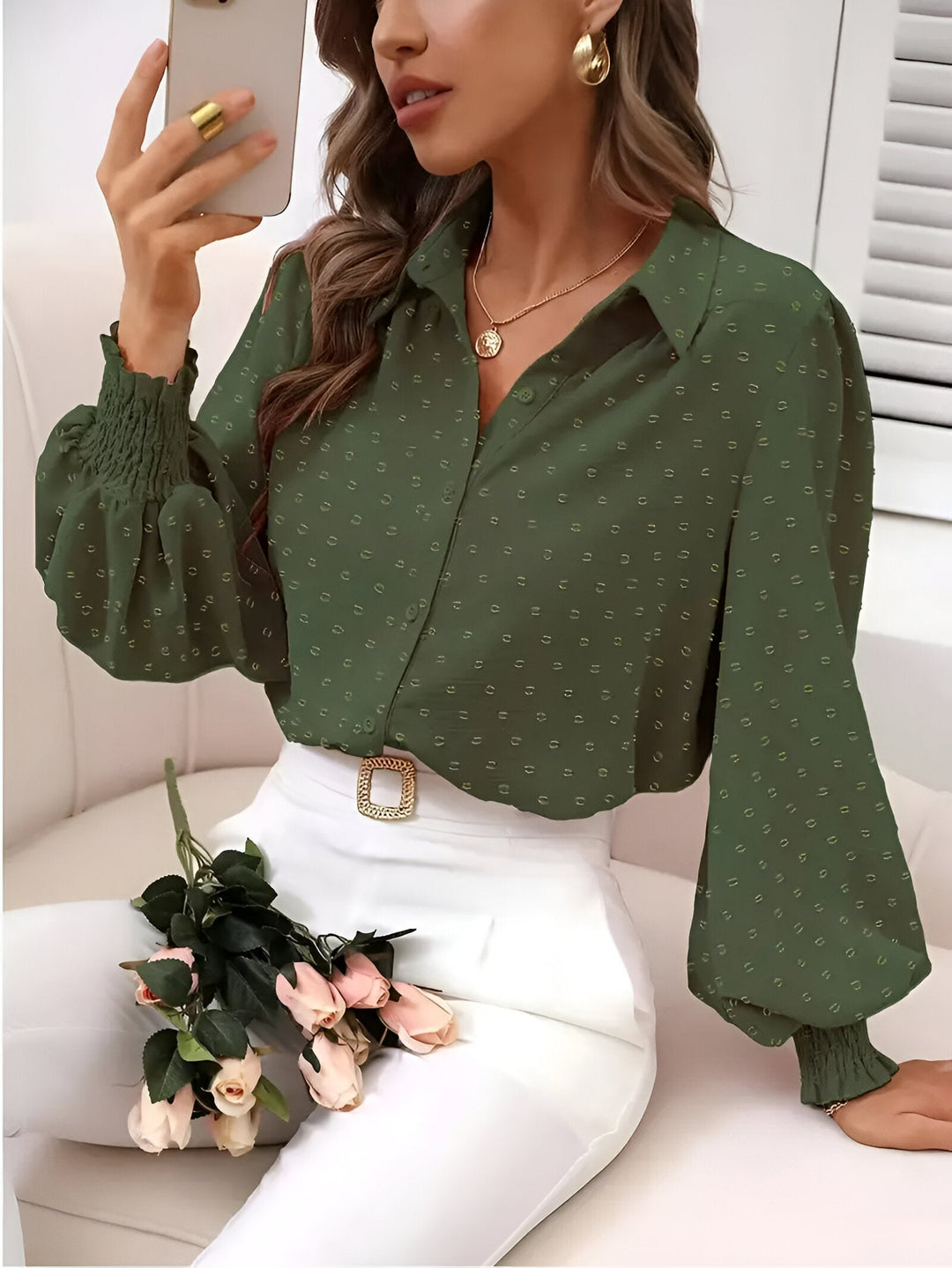 Model draagt een trendy damesblouse met elegante lantaarnmouwen en het unieke swiss dot patroon. Casual chic.
