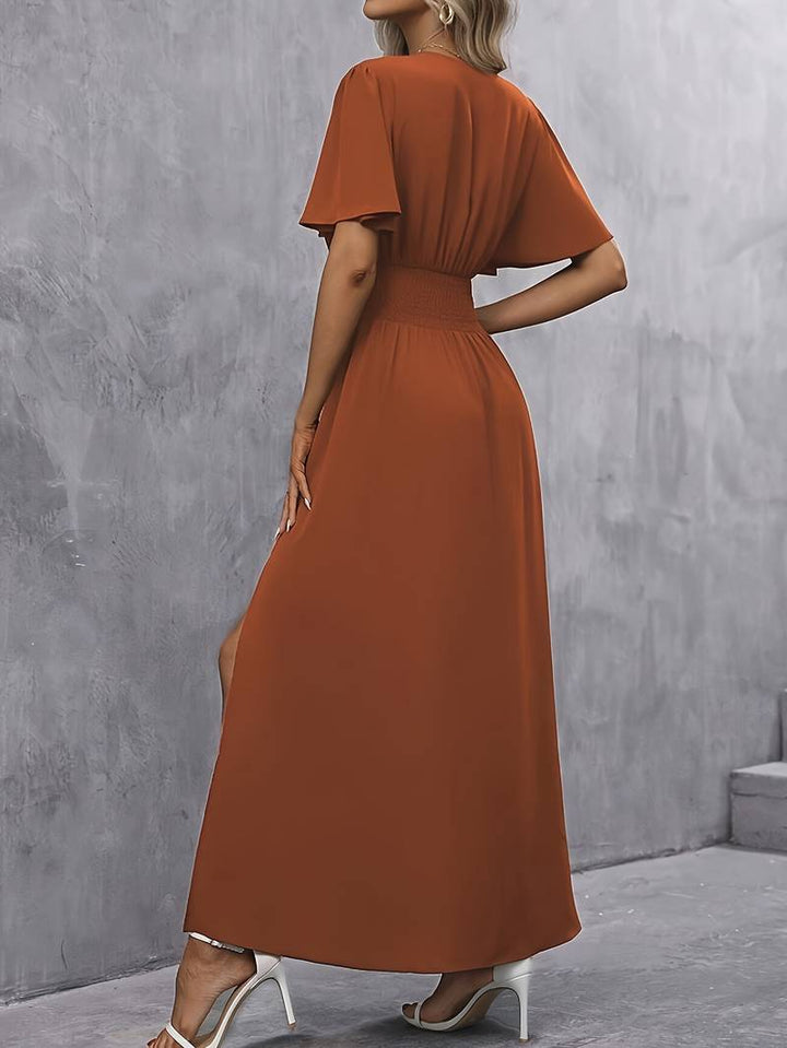 Detail van de stijlvolle split in karamel lange damesjurk, ideaal voor een casual of feestelijke look.