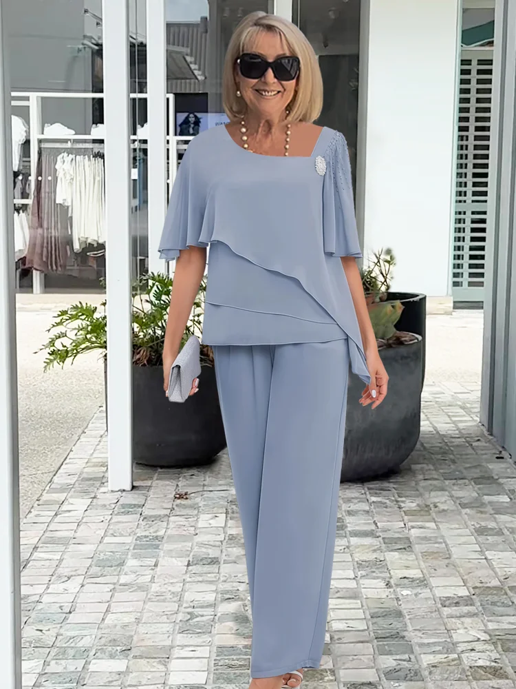Model draagt marineblauwe tweedelige set: asymmetrische top met overlay en zwierige wijde broek, ideale avondkleding.