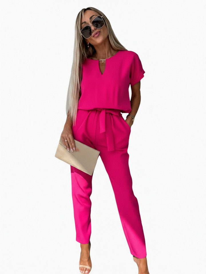 Elegante rozenrode dames jumpsuit met korte mouw, V-hals en strikceintuur; perfect voor zomerse dagen.