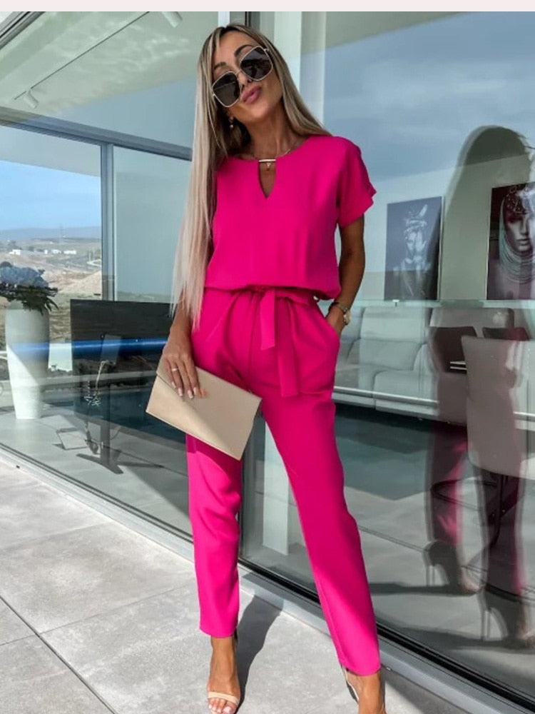Casual roze zomer jumpsuit voor dames, met korte mouw, V-hals en een stijlvolle strikceintuur.