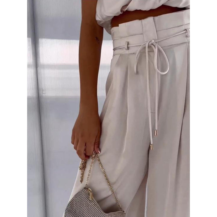 Stijlvolle tweedelige dames outfit met elegante haltertop en wijdepijpen broek. Zomerse chic.