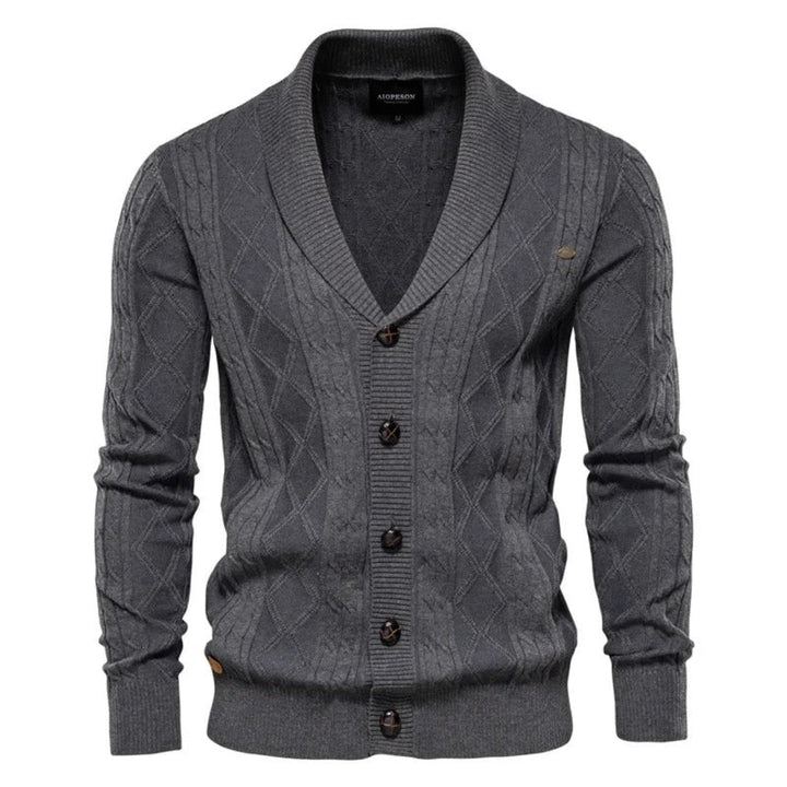 Detail van gebreid herenvest met sjaalkraag, knoopsluiting en verfijnd ruitpatroon. Geschikt voor heren kleding.