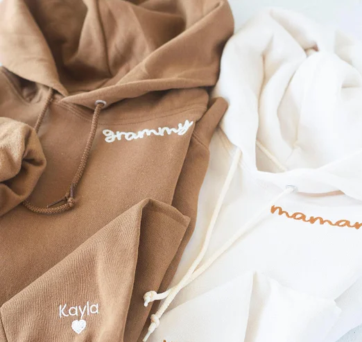 Zelfverzekerde vrouw draagt warme 'MOM' hoodie, gepersonaliseerd, ideaal casual kledingstuk voor Moederdag.