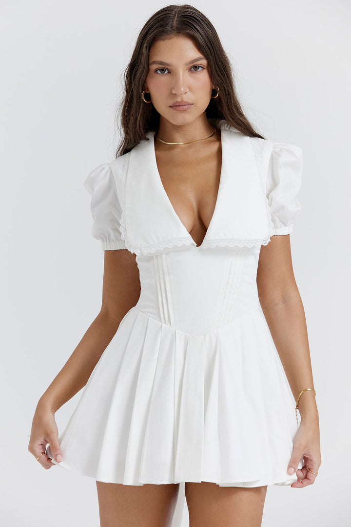 Detail van de V-hals en pofmouwen van deze geplooide dames mini-jurk; een elegante en klassieke look.