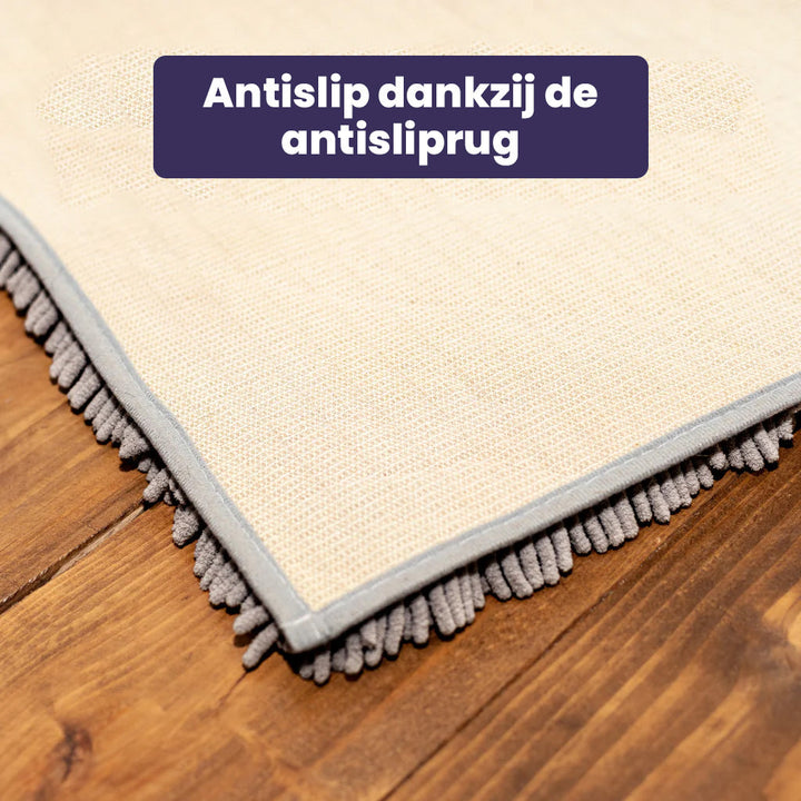 Beige schoonloopmat voor honden, waarop een vrolijke hond zijn poten veegt. Absorbeert vuil en vocht effectief.