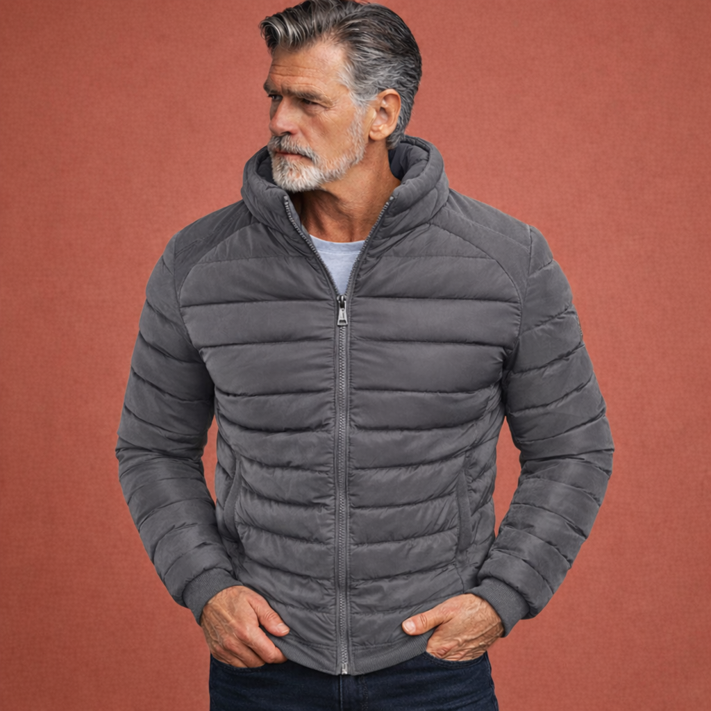 Model draagt casual heren gewatteerde jas met opstaande kraag. Stijlvolle overgangsjas met slanke pasvorm voor de man.