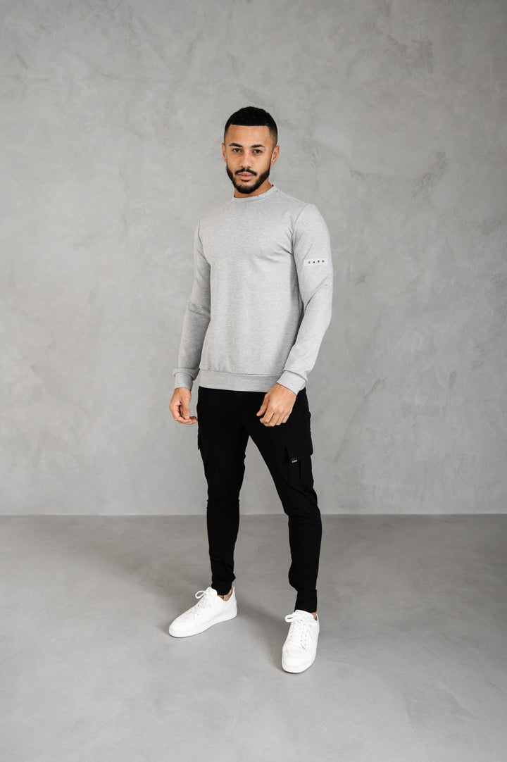 Man draagt zwarte slim fit heren cargobroek met cargozakken, elastische taille en atletische pasvorm.