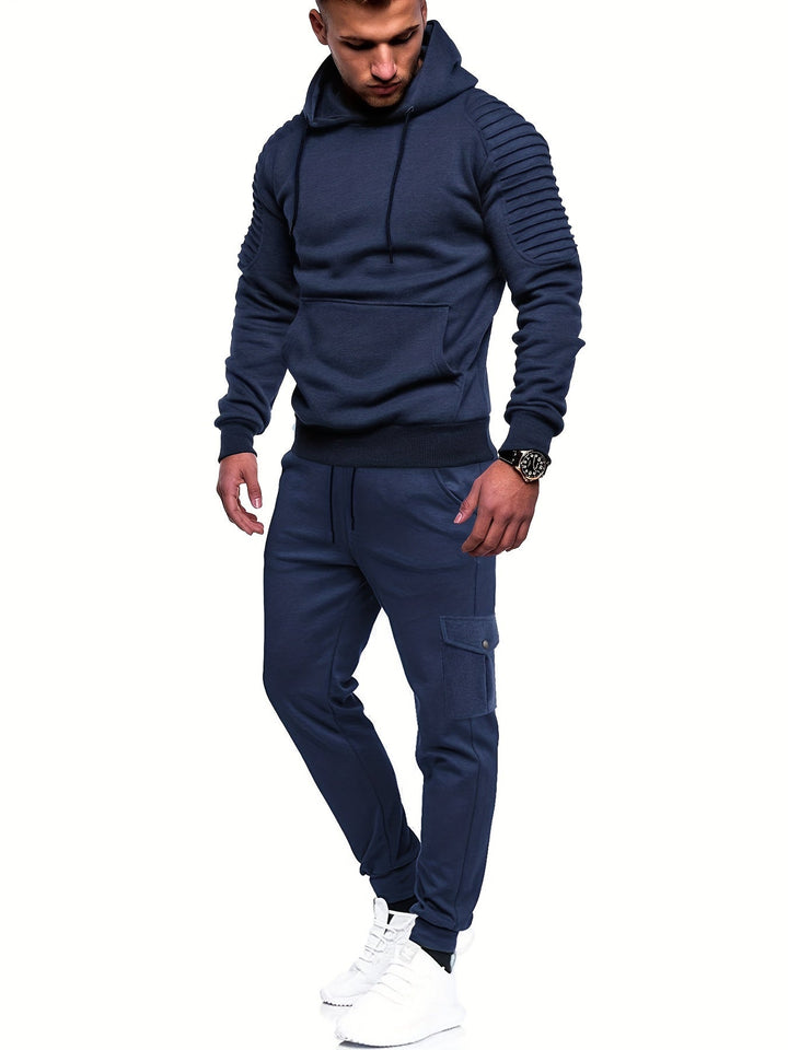 Man draagt modern heren sportoutfit; comfortabel trainingspak met lange mouwen en joggingsbroek voor actieve dagen.