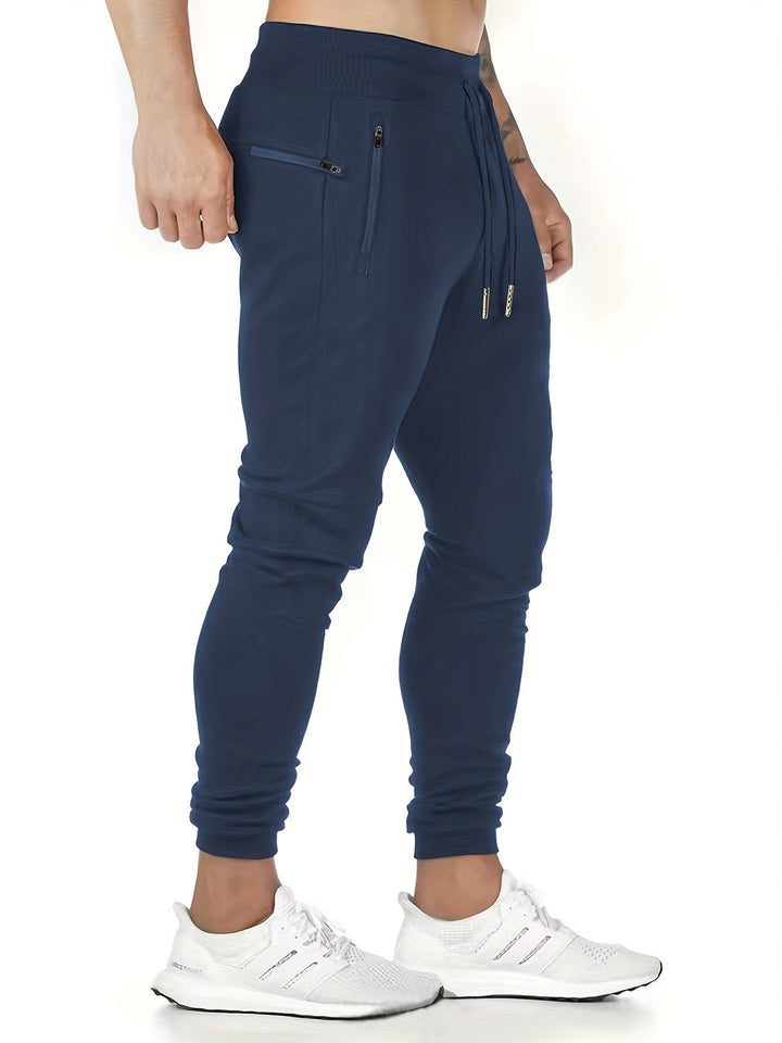 "Kastanjebruine heren joggingbroek van lichtgewicht polyester met ritszakken en trekkoord, ideaal voor lente en herfst."