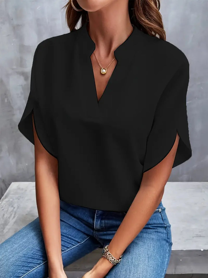 Model draagt de lichtgewicht damesblouse in het wit, gecombineerd met een broek.