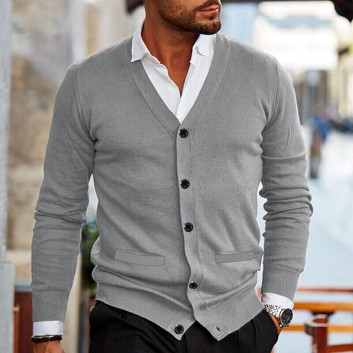 Man draagt stijlvol herenvest, klassieke cardigan over shirt, comfortabele wintermode perfect voor gelaagde look.