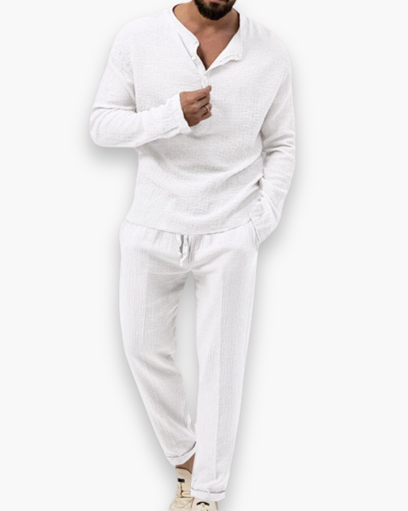 Model draagt chique heren zomerset: luchtige top en comfortabele broek. Perfect voor warme dagen.