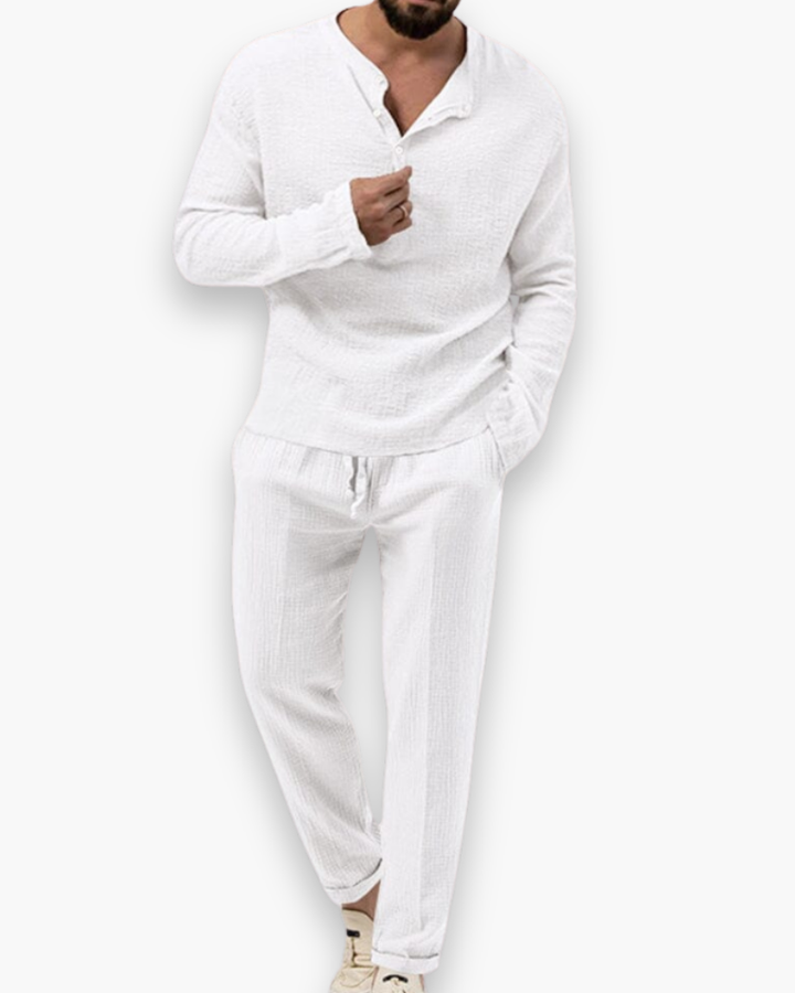 Model draagt chique heren zomerset: luchtige top en comfortabele broek. Perfect voor warme dagen.