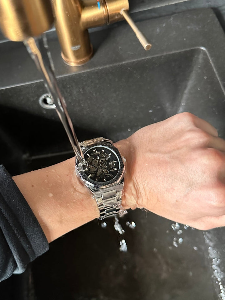 "Modern elegant herenhorloge met roestvrijstalen band, transparante wijzerplaat en open design. Tijdloos en stijlvol accessoi