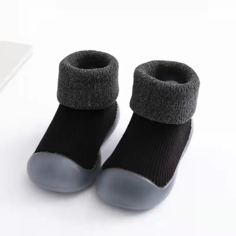 Lachende peuter loopt vrolijk op flexibele antislip sokschoenen, ideaal voor alle seizoenen.