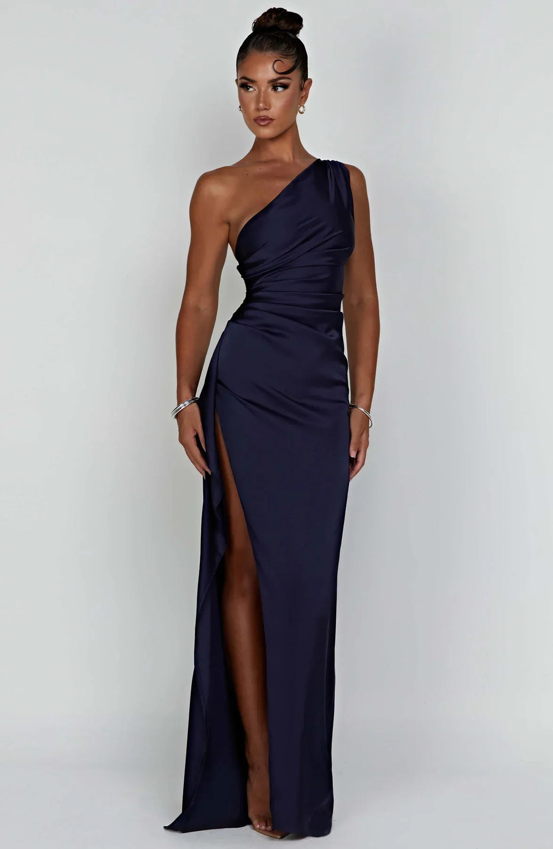 Modieuze zandkleurige splitjurk met geplooide accenten en one shoulder.
