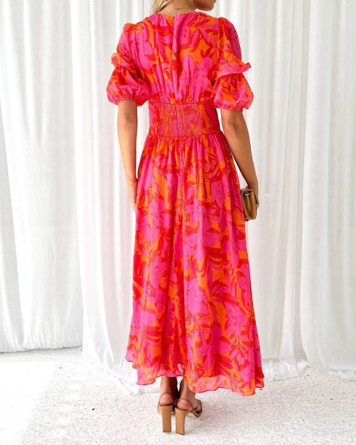 Zomerse dames maxi jurk met roze tropische print, V-hals en charmante pofmouwen. Een trendy boheemse feestjurk.