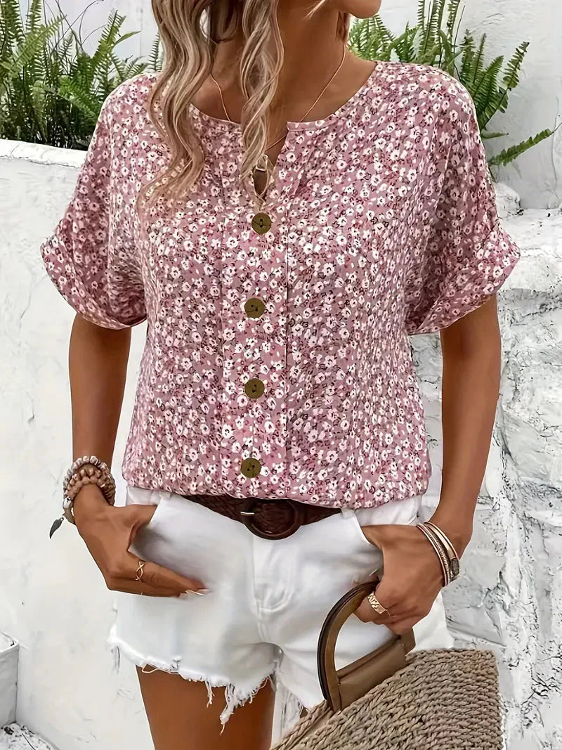 Vrouwelijke zomerblouse met bloemenprint, ronde hals en subtiele knoopsluiting, een stijlvolle roze top.