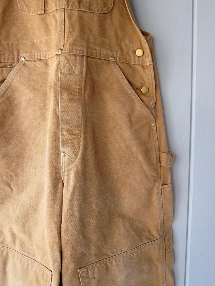 Detailopname van de verstelbare bretels op de duurzame unisex canvas werkoverall, voor een perfecte pasvorm.