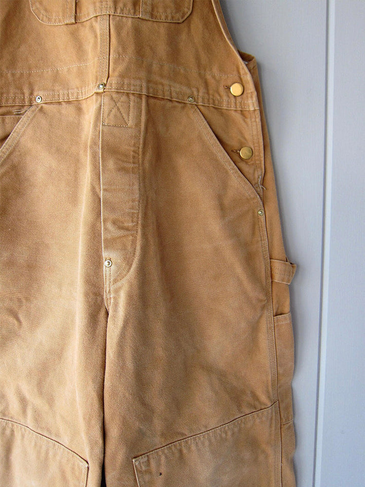 Detailopname van de verstelbare bretels op de duurzame unisex canvas werkoverall, voor een perfecte pasvorm.