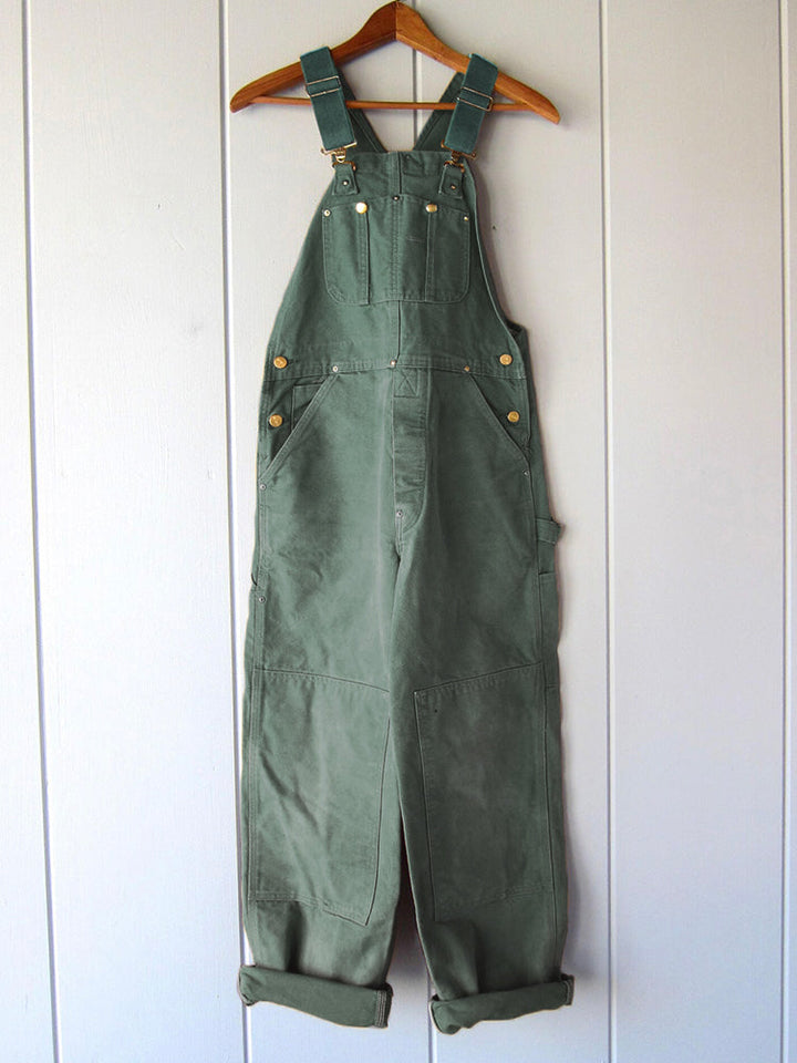 Unisex model draagt duurzame canvas werkoverall met verstelbare bretels, klaar voor elke klus en praktisch.
