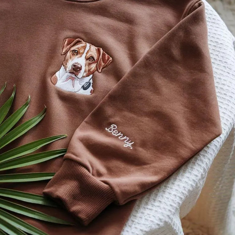 Close-up van een geborduurd hondenportret op een zacht sweatshirt. Perfect voor herdenking of als cadeau voor dierenliefhebbers.